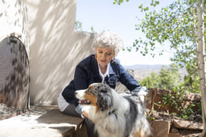 Woman sitting at a outdoor kiva fireplace with her Australian Shepard dog; online counseling; Santa Fe therapist, 87505, 87508