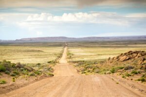 Lonely dirt road leads toward distant mountains in New Mexico evokes loneliness & despair. Learn emotional safety in relationships. PTSD therapy and CPTSD healing is possible. The Santa Fe Therapist online therapy. 87122, 87506, 87048, 87501